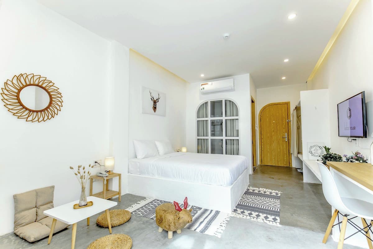 A modern bedroom with a bed, bedside table, lamp, decorative mirror, and a mounted deer head.
