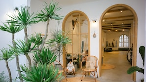 A hallway with a large arched doorway, a rattan chair, and a potted plant. -  LaDa's House Da Nang (Da Nang)