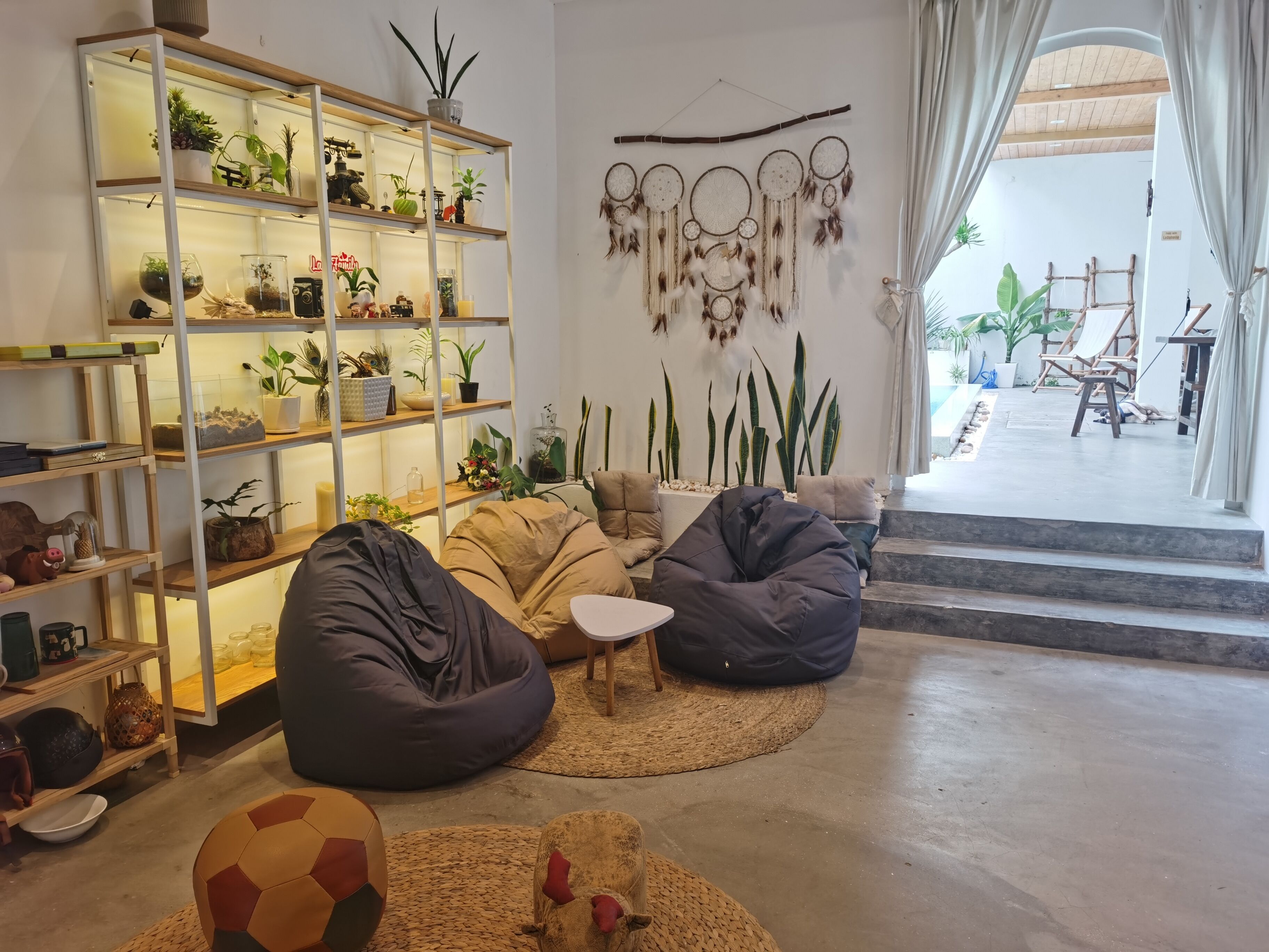 Uma sala de estar aconchegante com estante de livros, almofadas de chão, um sonho capturado e vista para o exterior.