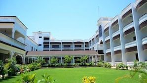 A hotel with multiple floors, a central courtyard with a lawn, and balconies on each floor. - White Peacock Resort Mtwapa (Mtwapa)