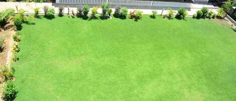 A large, well-maintained lawn with a covered patio area adjacent to a building with multiple seating arrangements.
