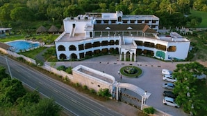 A large, white, multi-story building with a central courtyard, surrounded by lush greenery and a swimming pool. - White Peacock Resort Mtwapa (Mtwapa)