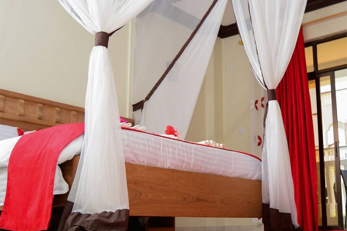 Uma cama com dossel, um cobertor vermelho e um tapete vermelho.