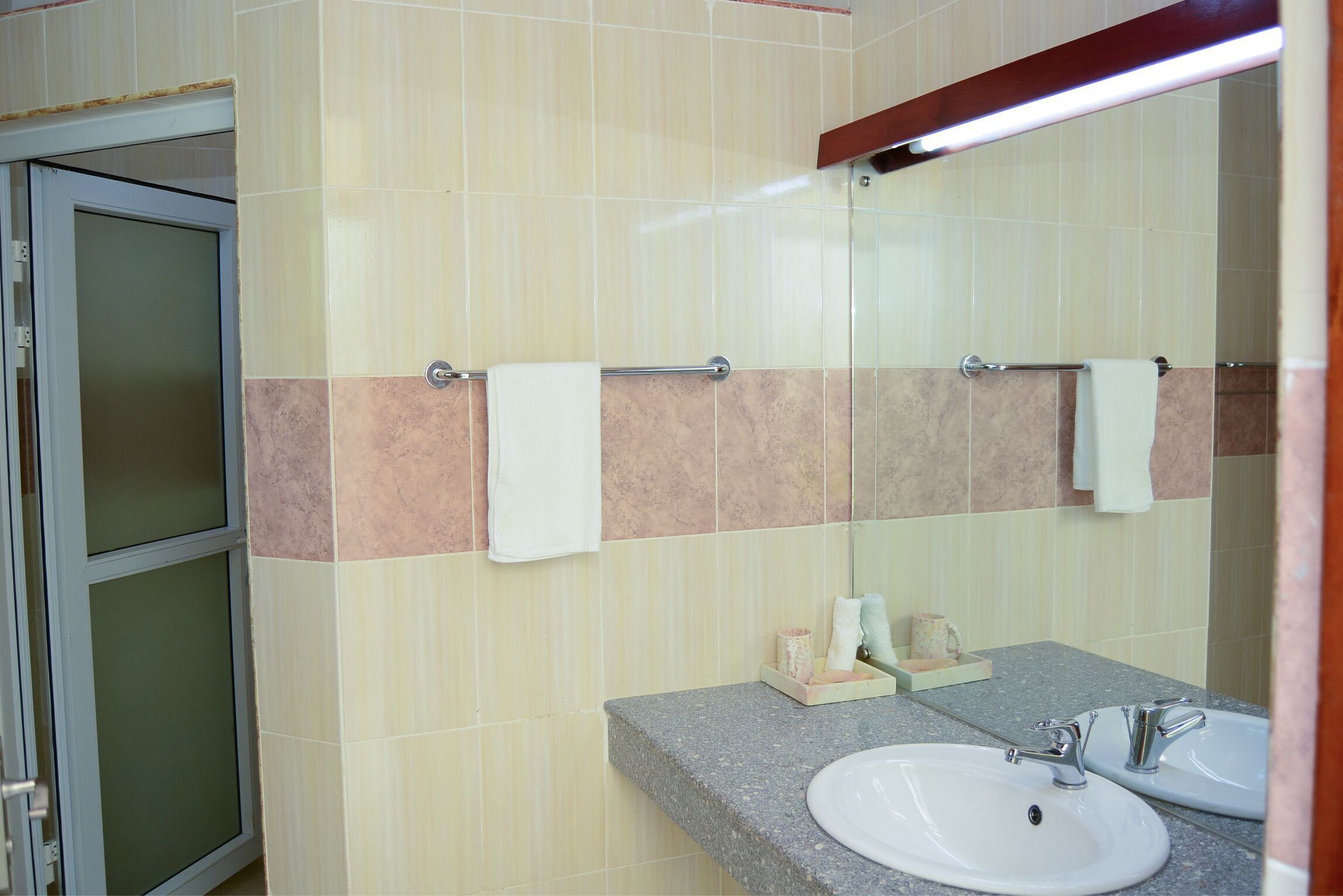Een badkamer met twee wastafels, een spiegel en een handdoekhouder.