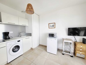 Una cocina compacta equipada con lavadora, microondas y cafetera.
