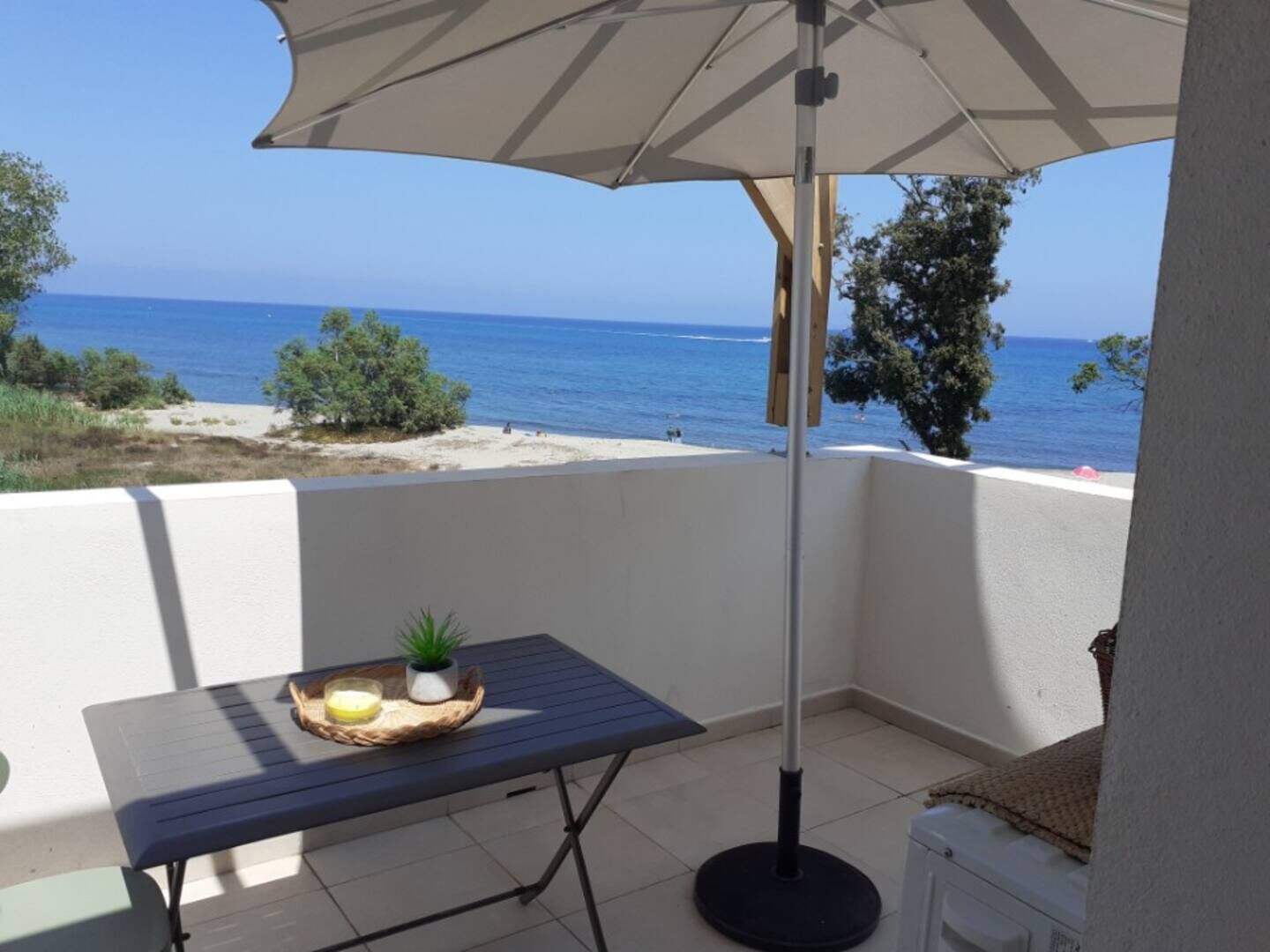 A balcony with a table, a small plant, and an umbrella.
