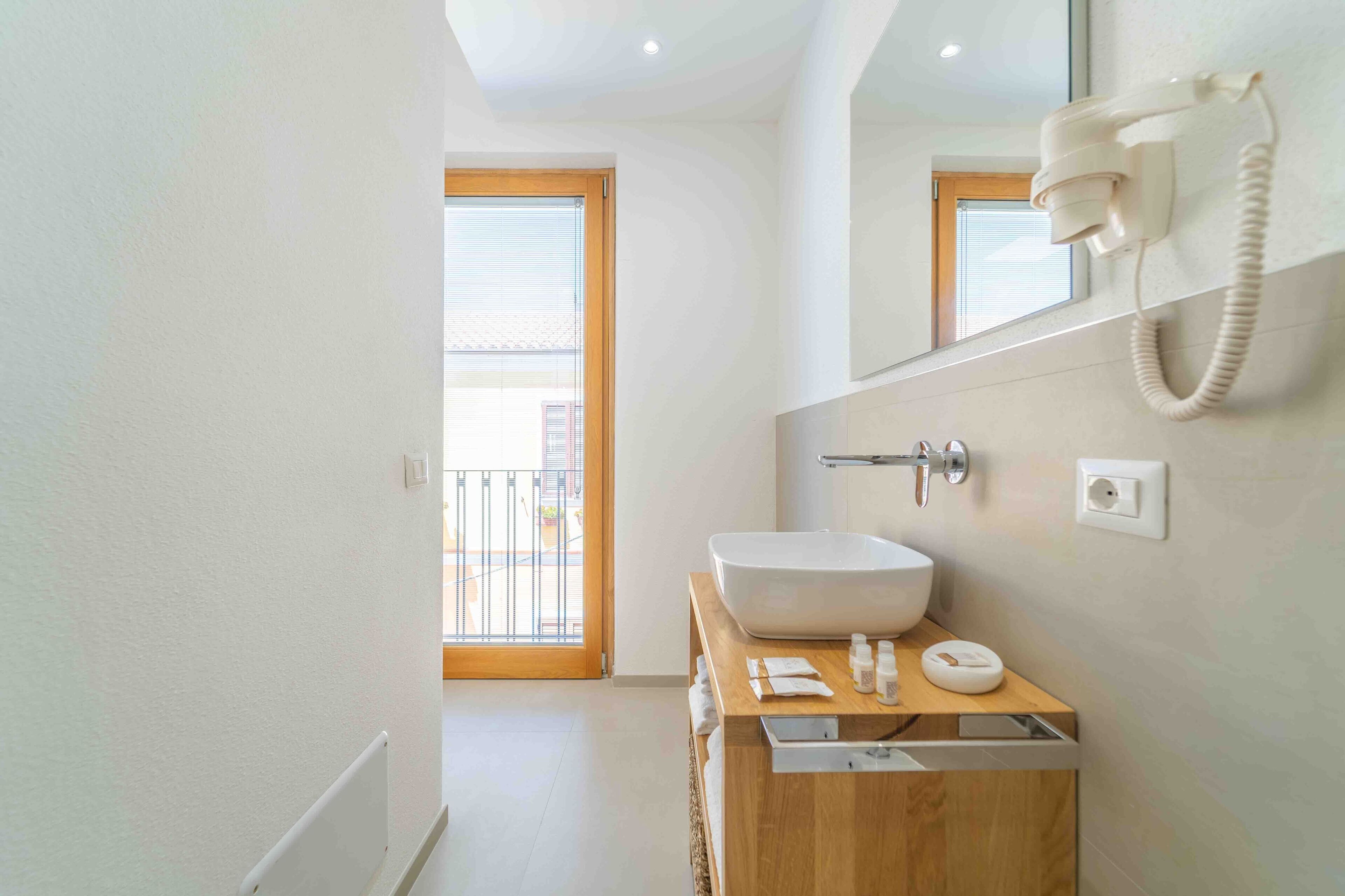 A modern bathroom with a wooden vanity, a large white sink, and a telephone.