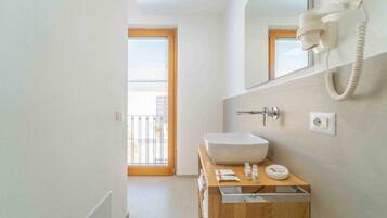 A modern bathroom with a wooden vanity, a large white sink, and a telephone.