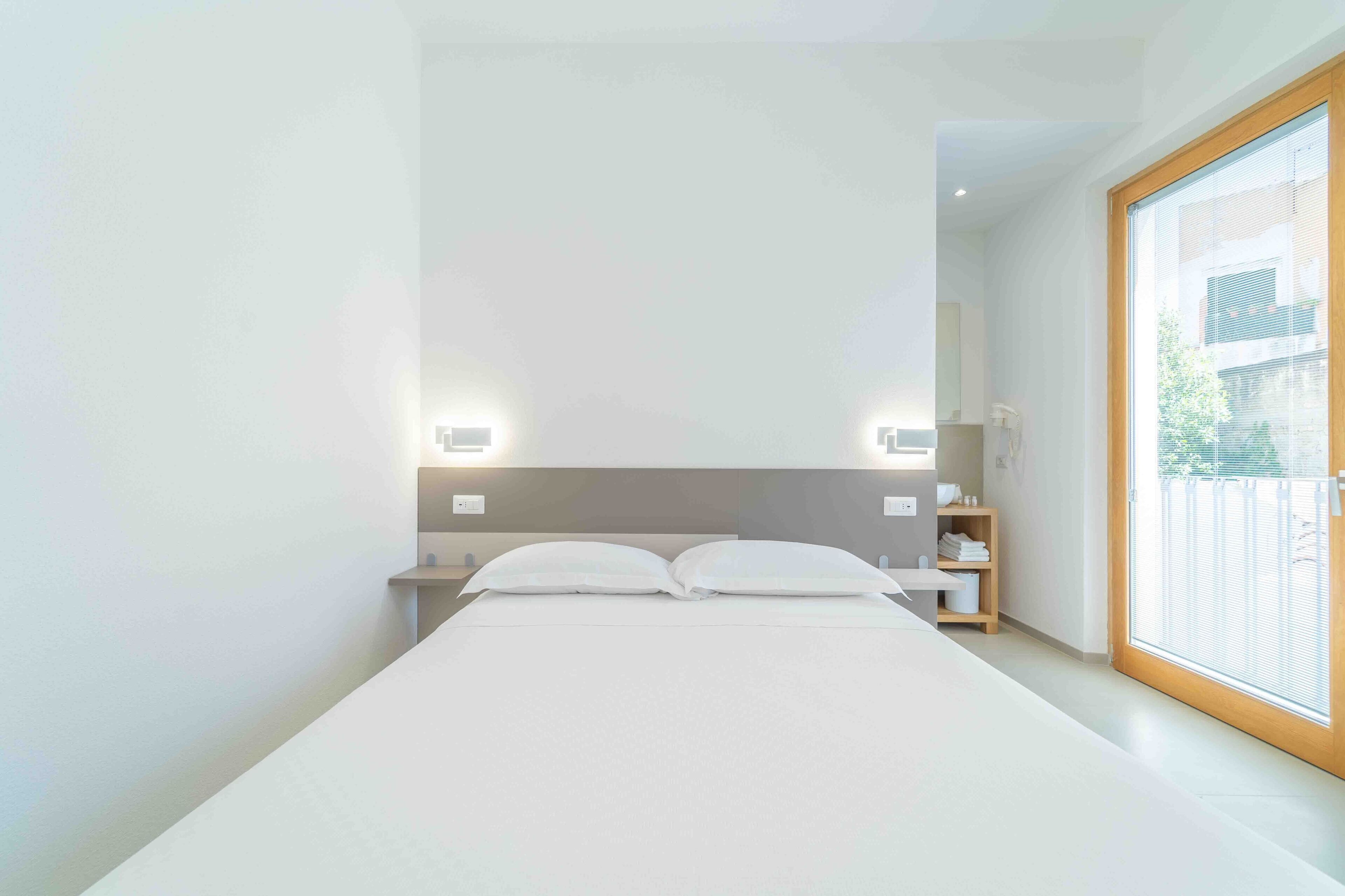 Et moderne hotelværelse med en stor seng, sengeborde og udsigt ud af vinduet.