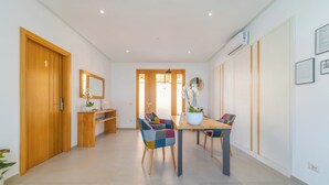 Un comedor moderno con una mesa de madera y sillas coloridas, una planta en maceta y un espejo en la pared.