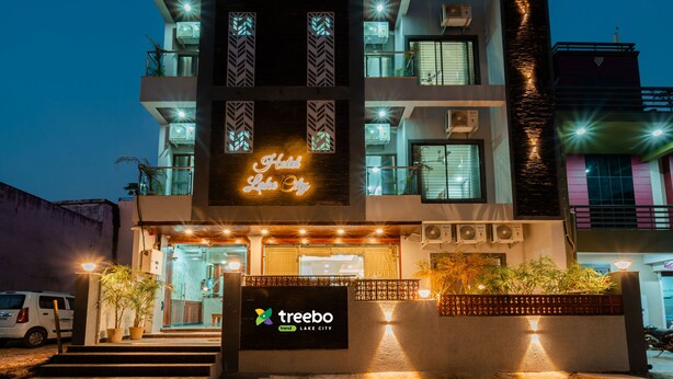 Ein mehrstöckiges Hotel mit einer auffälligen Neonreklame mit der Aufschrift "Hotel Lake City" und dem Schriftzug "treebo" im Erdgeschoss.