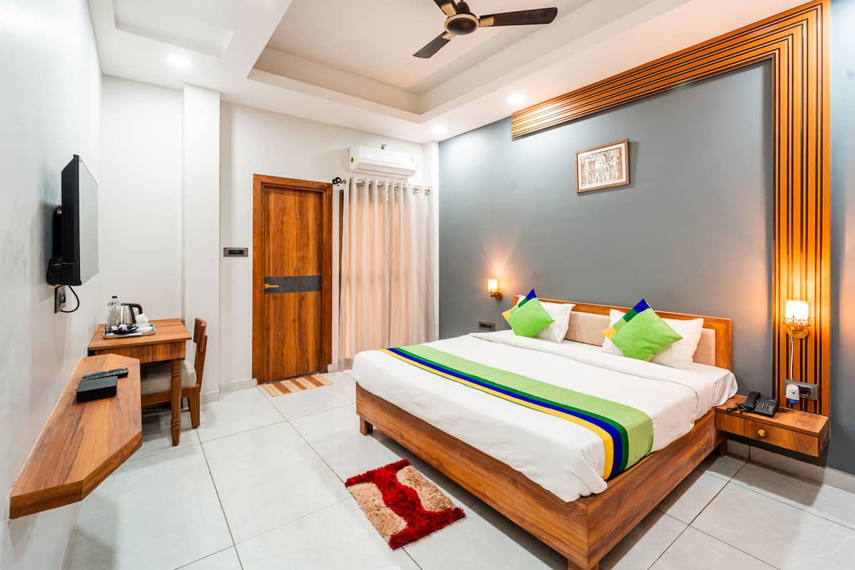 A hotel room with a bed, bedside table, TV, and a ceiling fan.