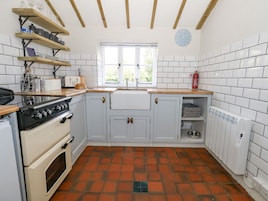 A kitchen with white cabinets, a stove, and a window.