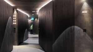 En moderne elevator lobby med mørk træbeklædning og oplyste etagenumre.