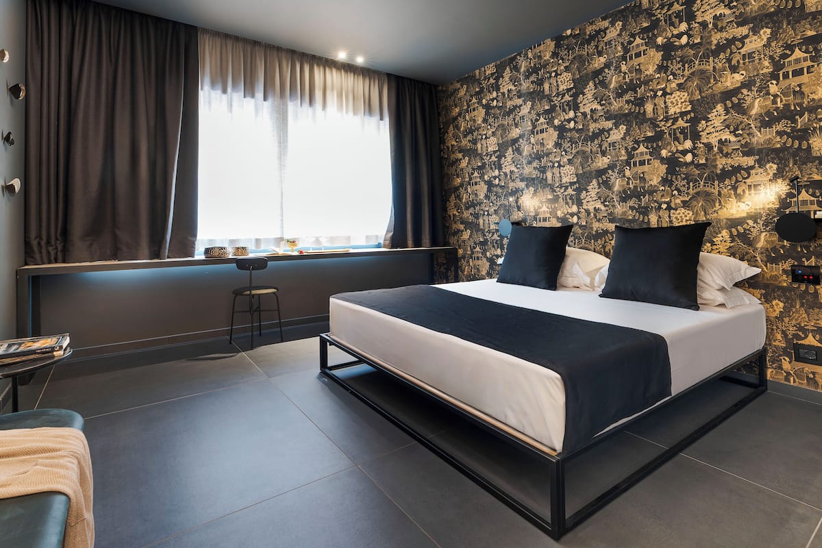A modern bedroom with a large bed, a desk, and a chair.