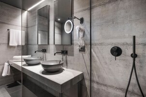 Un baño moderno con dos lavamanos amplios, un espejo, un secador de pelo y un cabezal de ducha de mano.