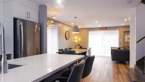 Una cocina moderna con una isla grande, electrodomésticos de acero inoxidable y una zona de comedor con mesa y sillas.