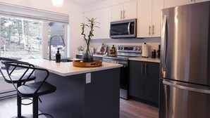 Una cocina moderna con una isla central, electrodomésticos de acero inoxidable y un amplio ventanal que ofrece vistas al exterior.