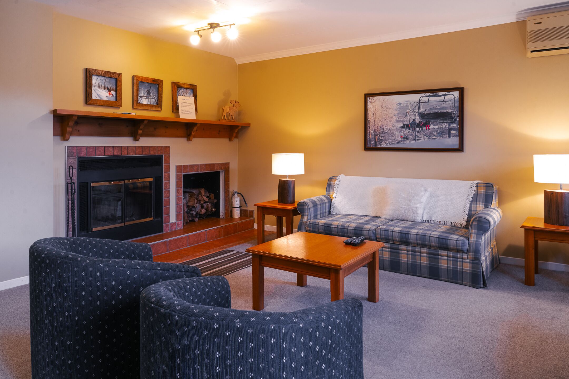 Una sala de estar acogedora con chimenea, un sofá, una mesa de centro y una lámpara.