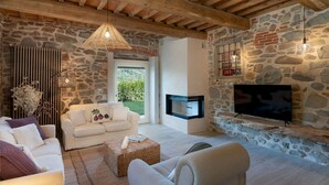 Ein gemütliches Wohnzimmer mit Steinwand, Kamin, Fernseher und einer bequemen Sitzecke.