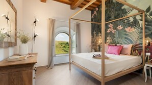 A bedroom with a four-poster bed, a wooden dresser, a mirror, and a view of the outdoors. - Casolare San Martino 12, Emma Villas (Pomarance)