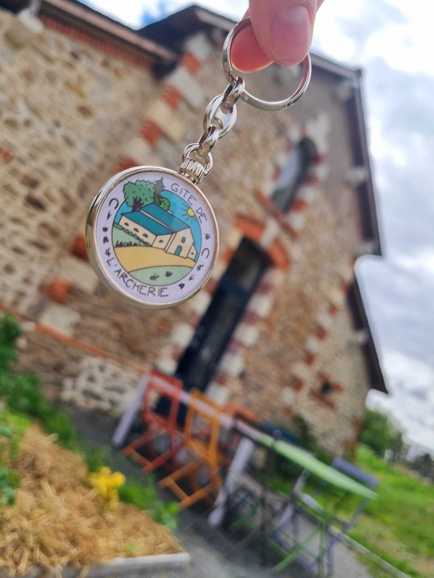 Ein Schlüsselanhänger mit Landschaftsmotiv, einem Metallring und einem Schlüssel.