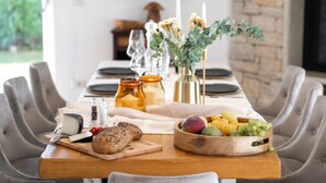 A dining table set with a cheese board, bread, and a bowl of fruit. - Villa Bincila Exclusive for 12 persons, pool, 6 bedrooms, pets allowed, garage (Labinci)