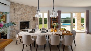 A dining area with a stone fireplace, a pool view, and a table set for six. - Villa Bincila Exclusive for 12 persons, pool, 6 bedrooms, pets allowed, garage (Labinci)
