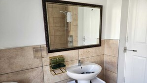 Een badkamer met een witte wastafel, een spiegel en een douche.