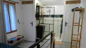 A compact bedroom with a bed, a small table, a wardrobe, and a shower area. - The little house (Ceyreste)