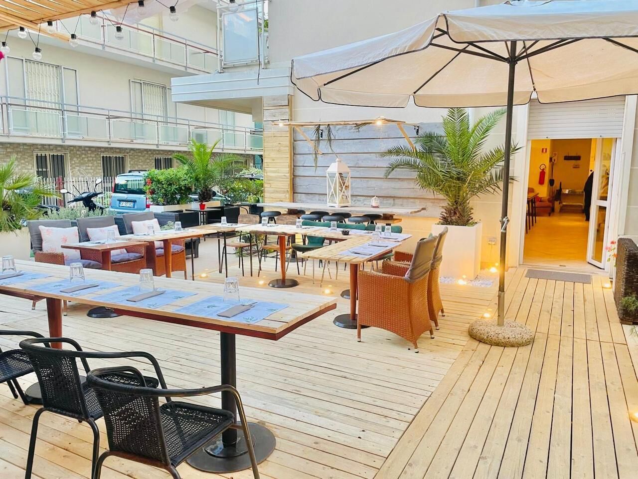 Un espace extérieur aménagé en terrasse, avec un sol en bois, des tables, des chaises et des parasols.