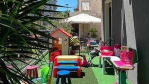 A children's play area with a small house, colorful play equipment, and a green artificial turf. - Hotel Soave Miriam (Rimini)