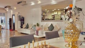A spacious living area with a large chessboard, a modern sofa, and a decorative glass vase. - Hotel Soave Miriam (Rimini)
