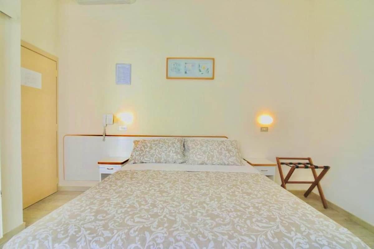 A bedroom with a bed, bedside tables, and a small wooden chair.