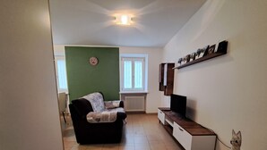 Una sala de estar con un sofá, un televisor y una estantería con fotografías.
