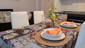Una mesa de comedor dispuesta con platos, servilletas y un jarrón de flores.