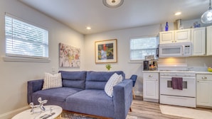 A compact living space with a sofa, a small table, a kitchen area with a microwave, and a stove. - 'the Dragonfly House' - Walk to Downtown Pensacola (Pensacola)