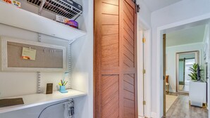 A hotel reception area with a wooden sliding door, a bulletin board with a 'Guest Info' sign, and a shelf with various items including a blue vase with pens. - 'the Dragonfly House' - Walk to Downtown Pensacola (Pensacola)