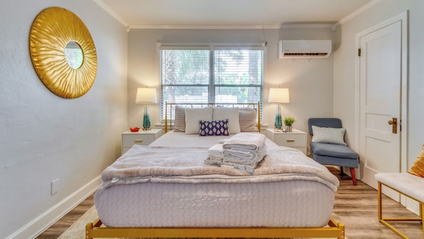 A bedroom with a bed, bedside lamps, a window, a ceiling fan, and a wall-mounted mirror. - 'the Dragonfly House' - Walk to Downtown Pensacola (Pensacola)