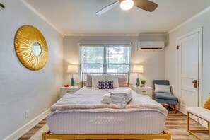 A bedroom with a bed, bedside lamps, a window, a ceiling fan, and a wall-mounted mirror.