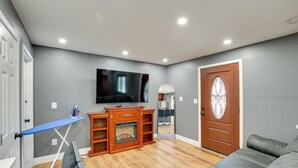 A living room with a flat-screen TV mounted on the wall, a wooden entertainment center, a fireplace, and a large mirror. - 3 Mi to Sofi Stadium! Hidden Gem in Hawthorne (Hawthorne)