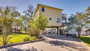 A two-story building with a covered patio area, outdoor seating, and a small boat dock. - Spacious Lake Livingston Home w/ Decks & Fire Pit! (Livingston)