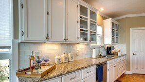 A kitchen with white cabinets, a granite countertop, and a window with blinds. - Spacious Lake Livingston Home w/ Decks & Fire Pit! (Livingston)
