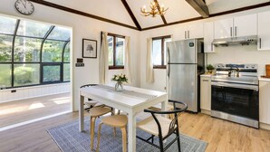 Una cucina moderna con un'ampia finestra, travi in legno, elettrodomestici in acciaio inossidabile e un'area pranzo con tavolo e sedie.