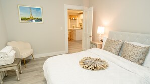 Une chambre d’hôtel avec un lit, une chaise, une table de chevet et une image de la Tour Eiffel accrochée au mur.