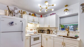 Una cocina con armarios blancos, un refrigerador, una estufa y un lavaplatos.