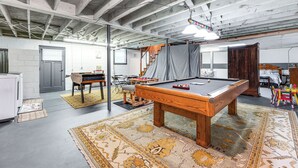 Une pièce spacieuse équipée d’une table de billard, d’un escalier et d’un espace de jeux.