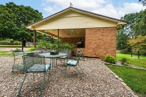 Relax in this patio area with a round table and four chairs, surrounded by a low brick wall and a gravel ground cover.