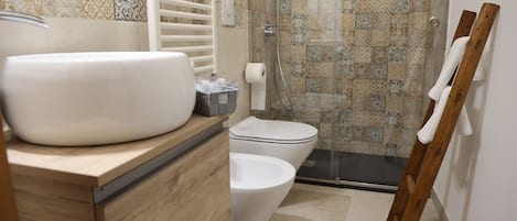 A bathroom with a large white sink, a toilet, and a shower area.