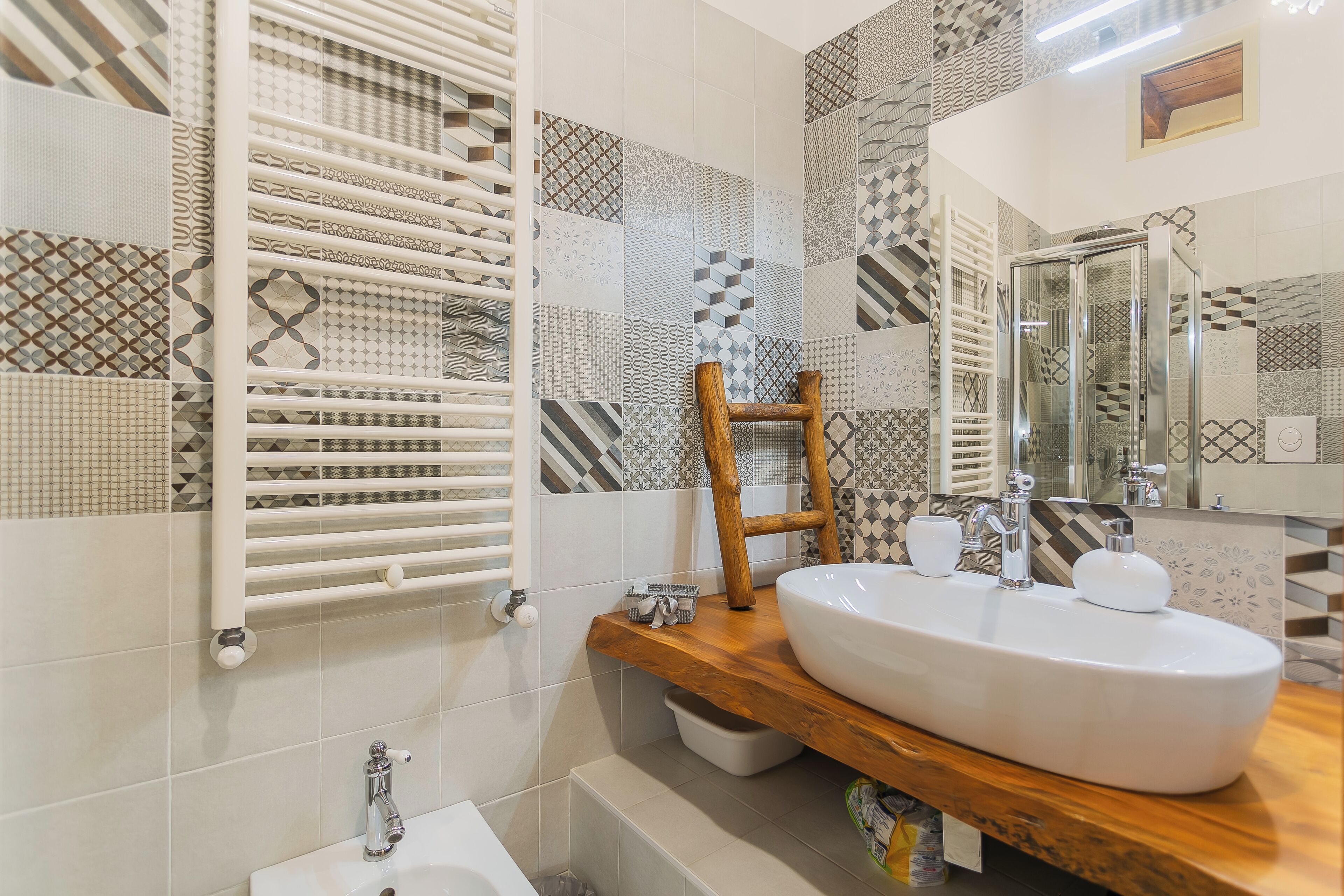 Un baño moderno con un lavamanos grande de color blanco, un mueble de tocador de madera, un perchero para toallas y una zona de ducha.